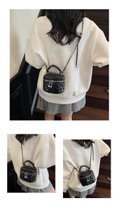 Close-up of quilted black mini bucket bag with heart pendant and leather chain strap