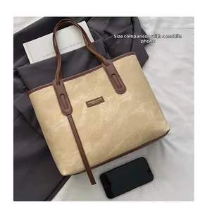 Detailed size comparison of the beige tote bag with a smartphone for scale reference