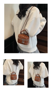 Detail of caramel brown quilted mini bag with heart charm zipper and gold chain strap