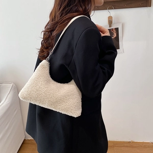 Sac à bandoulière en polaire blanc cassé sur modèle dans un décor intérieur épuré