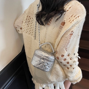 Mini sac matelassé argenté avec fermeture éclair cœur et chaîne porté par un mannequin