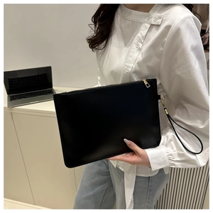 Close-up of black envelope clutch bag with gold zipper and detachable wrist strap