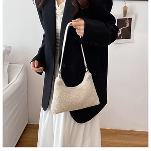 Detail of soft cream faux shearling tote bag styled with a professional black blazer