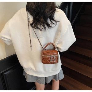 Détail d'un mini sac matelassé avec pendentif en cœur et bandoulière en chaîne