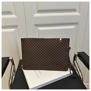 Gros plan d'une pochette vintage à motif marron avec zip doré sur un livre blanc