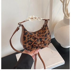 Detail of leopard print handbag featuring leather bows and lace-wrapped top handle