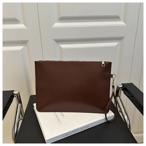 Détail d'une pochette en cuir marron foncé avec fermeture éclair dorée et dragonne