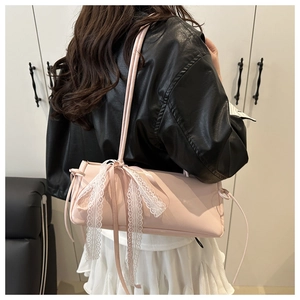 Pink baguette shoulder bag with a large white lace bow detail worn by a model