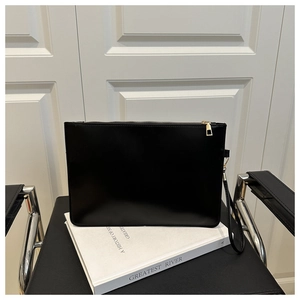 Détail d'une pochette enveloppe noire en cuir minimaliste avec fermeture éclair dorée