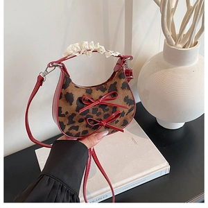 Detail of leopard print faux fur handbag with red leather trim and lace handle wrap