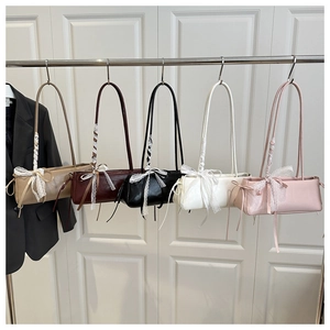 Detail of five assorted leather underarm bags with lace bow accents on a display rack