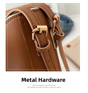 Detail of brown leather bag strap with gold metal buckle and insect-themed decoration