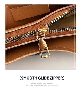 Close-up of smooth gold-tone metal zipper on a brown textured leather bucket bag