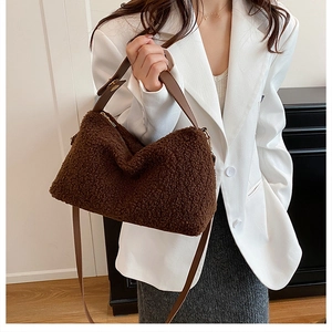 Close-up of brown teddy faux fur handbag with leather straps worn over a white blazer