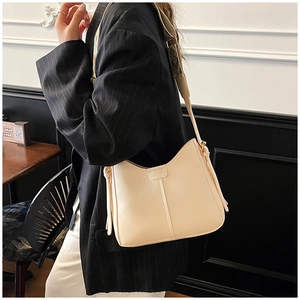 Close-up of cream crossbody bucket bag featuring a wide geometric woven shoulder strap