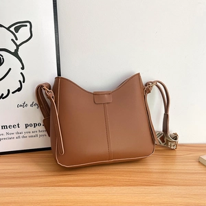 Close-up of brown leather bucket bag with vintage geometric embroidered wide strap