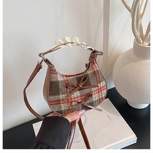 Detail of checkered woolen crescent bag with leather bows and lace pleated handle