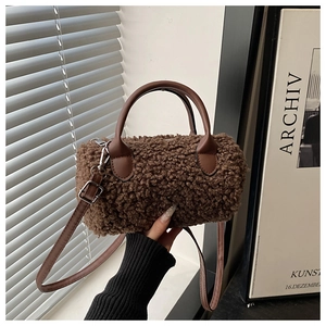 Dettaglio della borsa cilindrica in peluche marrone con manico in pelle e finiture in metallo