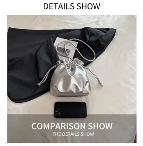 Close-up of silver metallic bucket bag showing size comparison with a smartphone