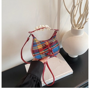 Detailed close-up of plaid fabric texture with leather bows and lace trim on handbag