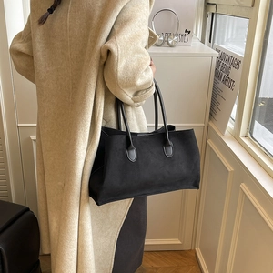 Grand sac cabas noir en daim minimaliste présenté lors d'un shooting photo de mode urbaine