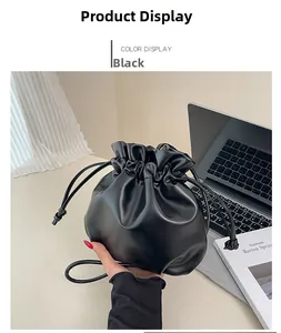 Detail of a black drawstring cloud bucket bag with textured leather and a thin shoulder strap