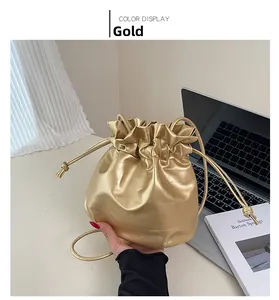 Close-up of a gold drawstring bucket bag in soft PU leather on a minimalist desk setup