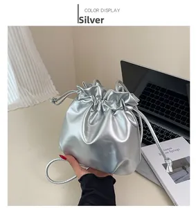 Detail of silver metallic drawstring bucket bag shown in a minimalist urban setting
