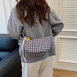 Borsa a tracolla a mezzaluna a quadretti con ciondolo a stella indossata da una modella