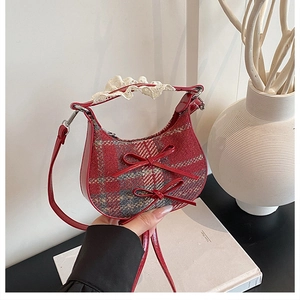 Detail of red plaid handbag with leather bows, lace trim, and crossbody strap