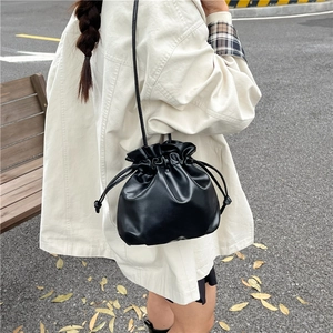 Moderna borsa a secchiello nera con coulisse indossata da una modella in stile street