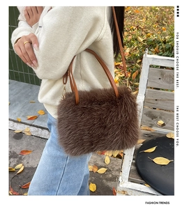 Detail of dark brown plush shoulder bag with leather handles shown on a model
