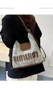 Close-up of gray canvas tote bag with brown leather accents on a model's shoulder