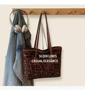 Detailed close-up of leopard print tote bag with brown leather handles hanging on a rack