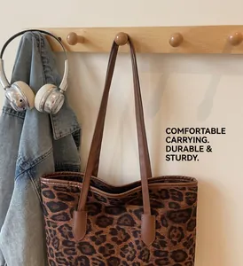 Detailed view of leopard print tote bag hanging with leather straps in home setting