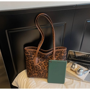 Detailed view of leopard print tote bag next to a laptop showing large capacity size