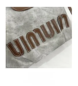Detail of vintage gray washed fabric backpack with brown leather UINUIN letter patch