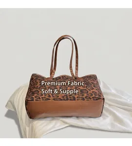 Detail of leopard print tote bag with brown leather handles next to lifestyle props