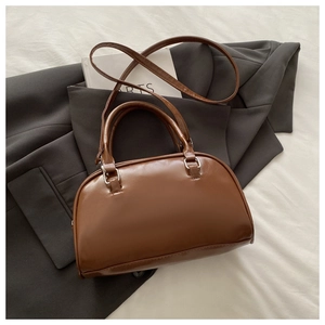 Macro shot of retro brown leather Boston bag showing fine texture and silver metal buckles