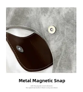 Close-up of a premium magnetic metal buckle on a vintage denim tote bag with leather trim