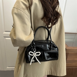 Chic black patent leather bowling bag with pearl bow charm and twin front pockets