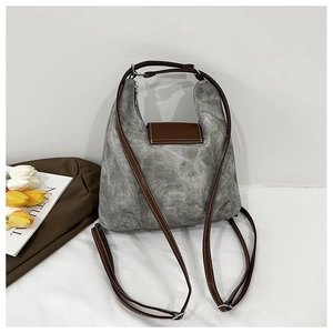 Detail of gray washed canvas backpack with brown leather straps and white topstitching