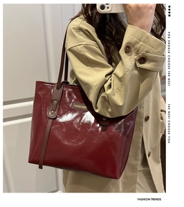 Close-up of burgundy patent leather tote bag with glossy finish and long brown handles