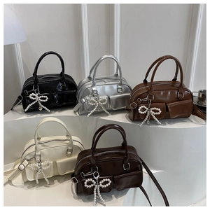 Detailed view of five multi-colored shiny PU leather handbags with pearl bow charms