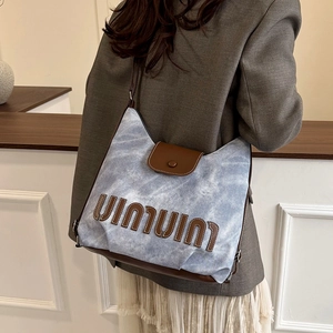 Retro washed blue canvas and brown leather tote bag worn as a shoulder bag on a model