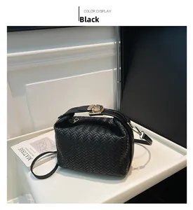 Detailed view of black woven crossbody bag with gold square buckle and metal hardware