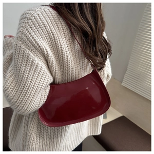 Macro detail of glossy dark red patent leather bag with mirror finish texture