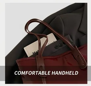 Close-up of deep burgundy patent leather tote bag handles with reinforced stitching