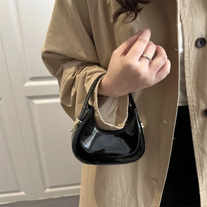 Mini crescent shoulder bag in glossy black patent leather with elegant gold hardware