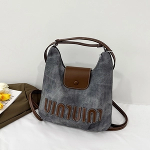 Detail of vintage washed denim tote bag with leather straps and decorative embroidery